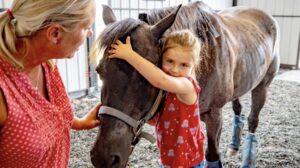 Young girl hugging horse in a therapy session